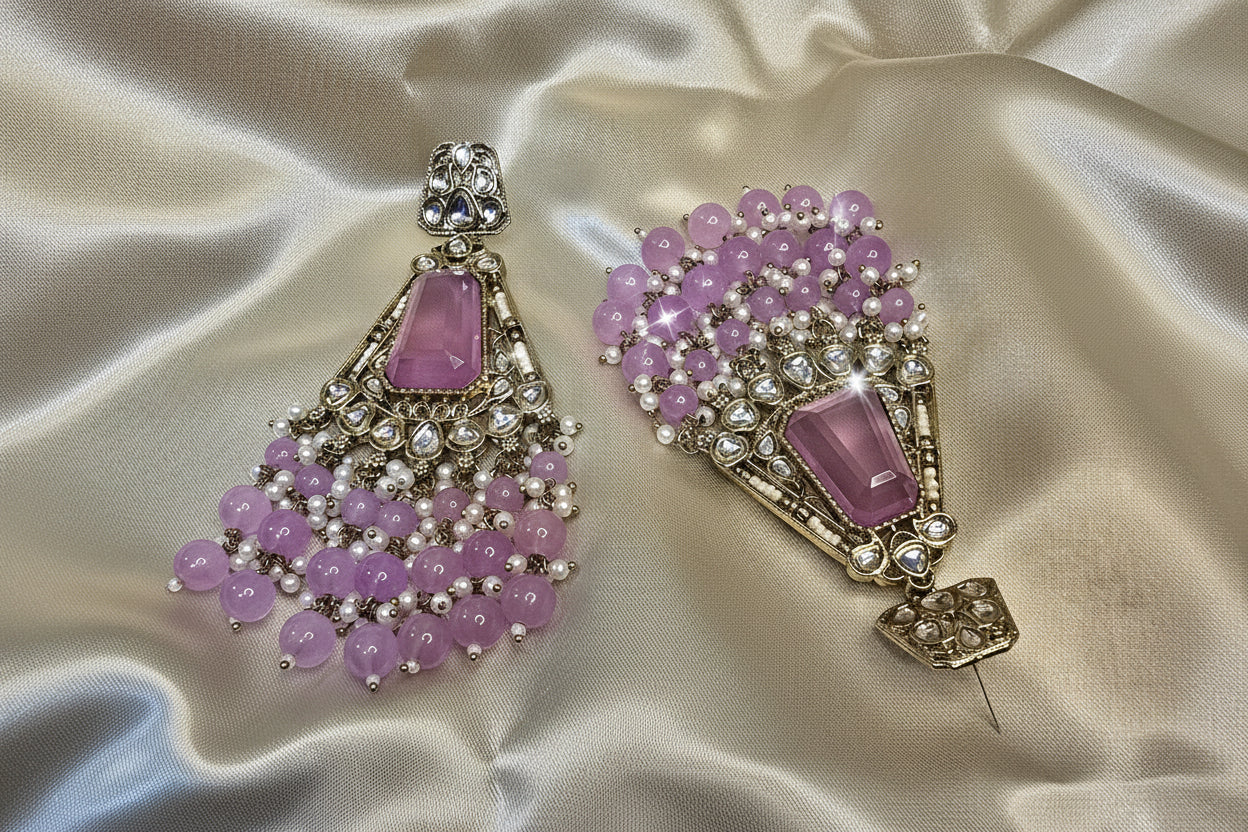 Pair of ornate earrings with purple stones on a satin background