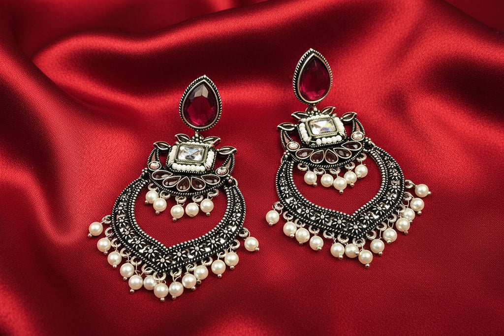 Ornate earrings with pearls on a red fabric background