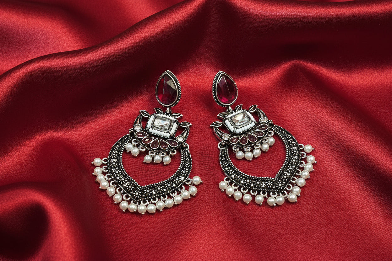 Ornate earrings with pearls on a red fabric background