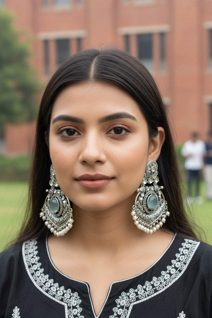 Ornate silver earrings with pearls on a red fabric background
