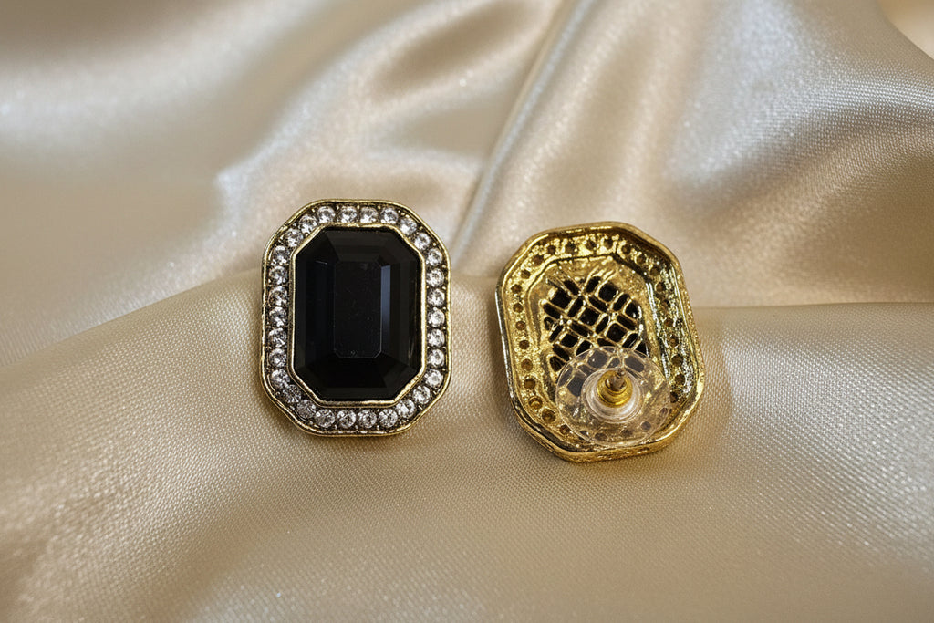 Gold and black decorative buttons on a beige fabric background