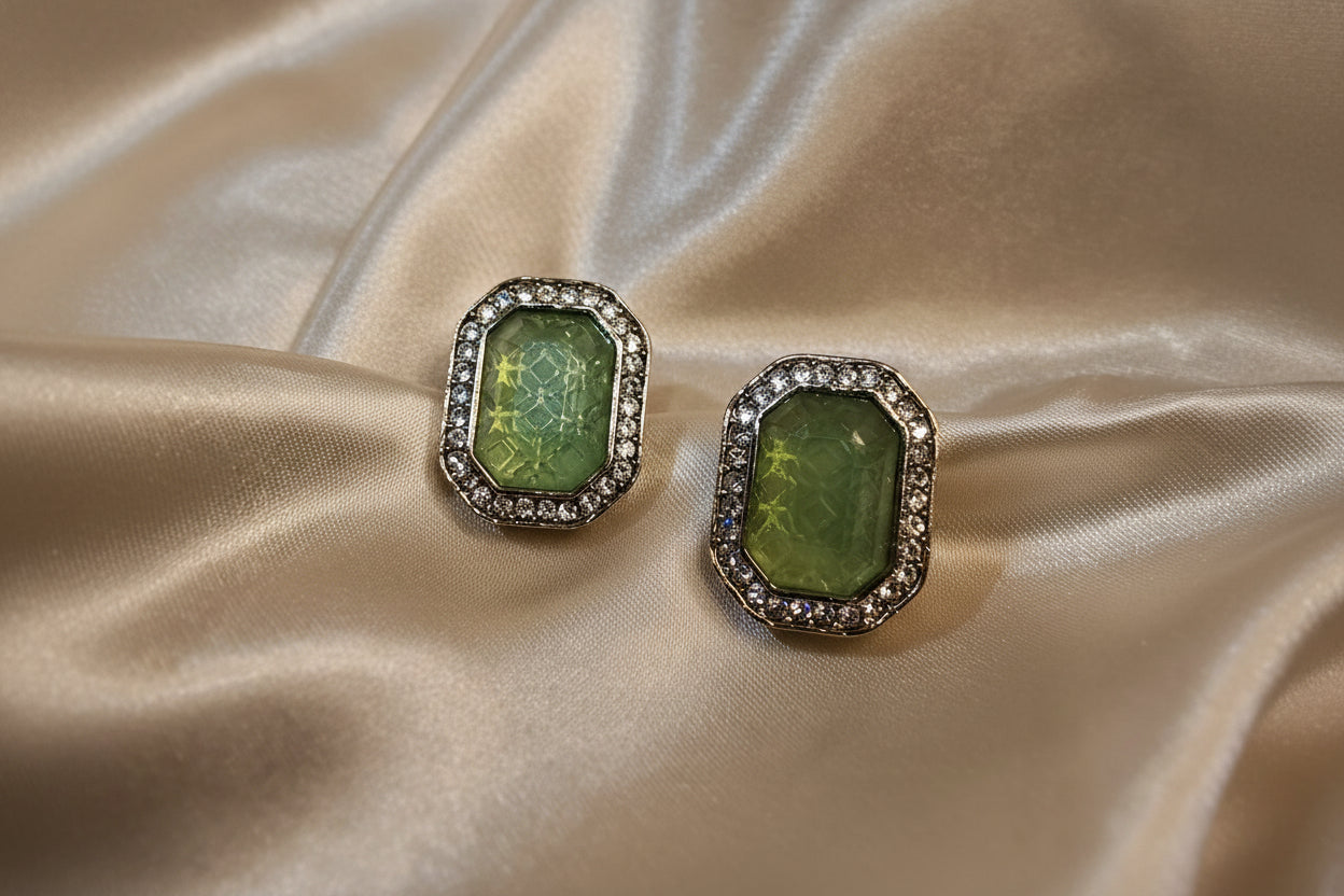 Pair of earrings with green gemstones on a satin surface