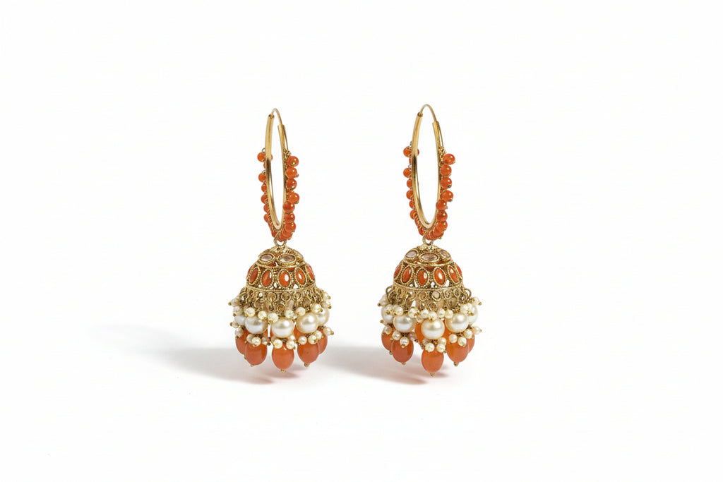 Pair of gold hoop earrings with red and white gemstones on a satin surface